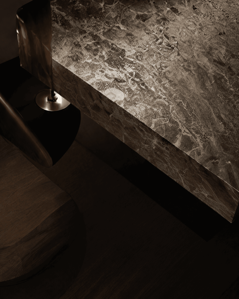 Interiorismo de lujo en Madrid con mesa de mármol oscuro, iluminación cálida y diseño contemporáneo minimalista